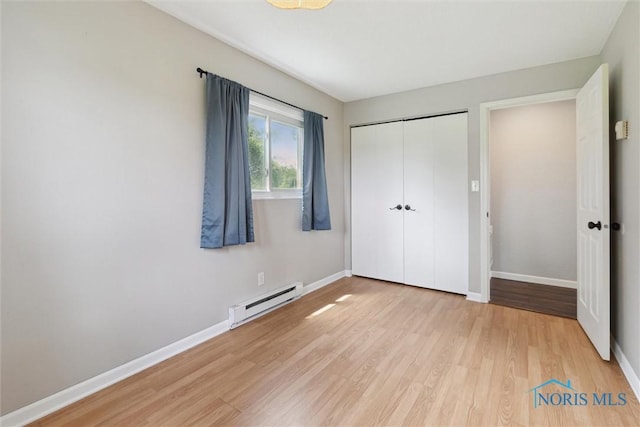 10540 Veler Rd, Curtice, OH 43412 - unfurnished bedroom featuring a baseboard radiator, light wood-style flooring, baseboards, and a closet