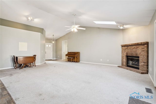209 E Sawmill Rd, Findlay, OH 45840 - carpeted living room with a brick fireplace, a ceiling fan, baseboards, lofted ceiling, and a skylight