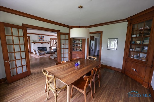 5243 Flanders Rd, Toledo, OH 43623 - dining area with a fireplace, wood finished floors, baseboards, and ornamental molding