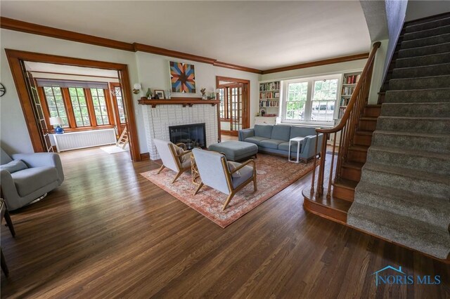 5243 Flanders Rd, Toledo, OH 43623 - living room featuring radiator, stairway, ornamental molding, wood finished floors, and a brick fireplace