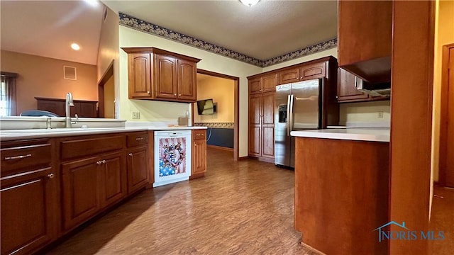 12327 Buckeye Dr, Paulding, OH 45879 - kitchen with stainless steel fridge, light countertops, white dishwasher, dark wood-type flooring, and brown cabinetry