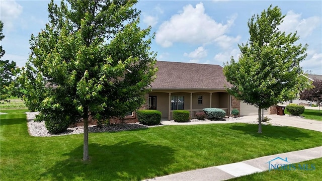 12327 Buckeye Dr, Paulding, OH 45879 - view of front facade with a front lawn, concrete driveway, a shingled roof, brick siding, and covered porch