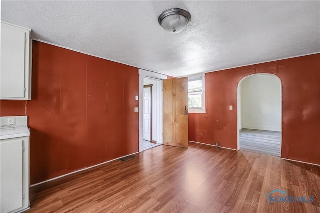 446 Center St, Findlay, OH 45840 - unfurnished room featuring a textured ceiling, arched walkways, and light wood-style flooring