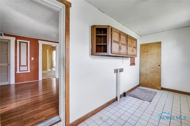 446 Center St, Findlay, OH 45840 - laundry room featuring a textured ceiling, baseboards, arched walkways, and light tile patterned floors