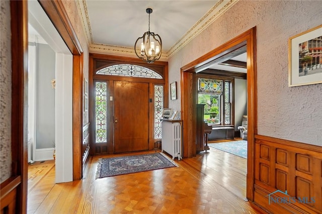 1100 S Main St, Findlay, OH 45840 - foyer with healthy amount of natural light, a chandelier, a textured wall, crown molding, and a wainscoted wall