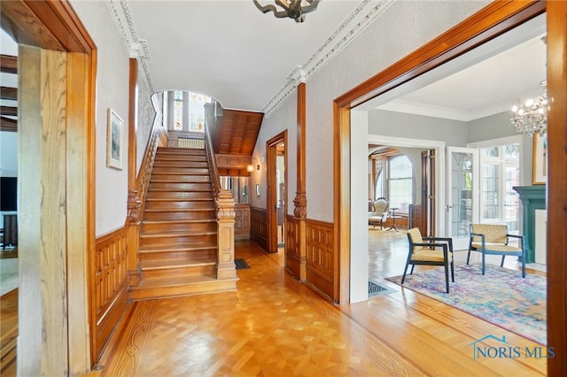 1100 S Main St, Findlay, OH 45840 - stairs with wainscoting, a chandelier, ornamental molding, wooden walls, and parquet flooring