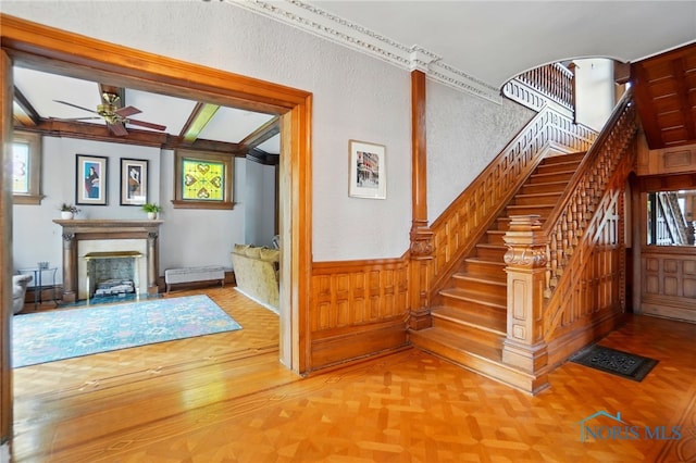 1100 S Main St, Findlay, OH 45840 - staircase with ceiling fan, a fireplace, wainscoting, wood walls, and parquet flooring