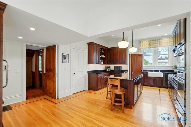 1100 S Main St, Findlay, OH 45840 - kitchen featuring light wood finished floors, a sink, a center island, dark countertops, and a breakfast bar area