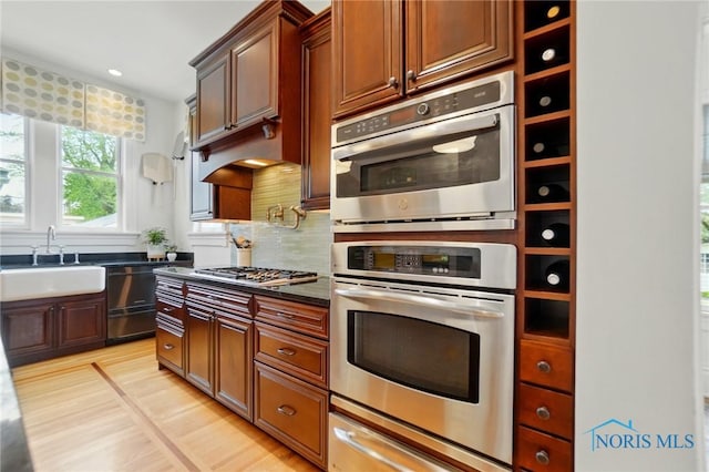 1100 S Main St, Findlay, OH 45840 - kitchen featuring a sink, stainless steel appliances, dark countertops, a warming drawer, and light wood finished floors