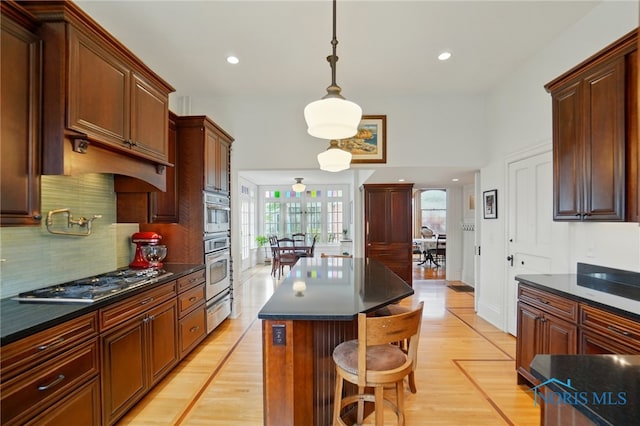 1100 S Main St, Findlay, OH 45840 - kitchen with stainless steel gas cooktop, dark countertops, backsplash, a breakfast bar, and hanging light fixtures