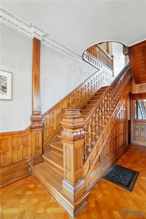 1100 S Main St, Findlay, OH 45840 - staircase featuring a high ceiling, a textured wall, wooden walls, and wainscoting