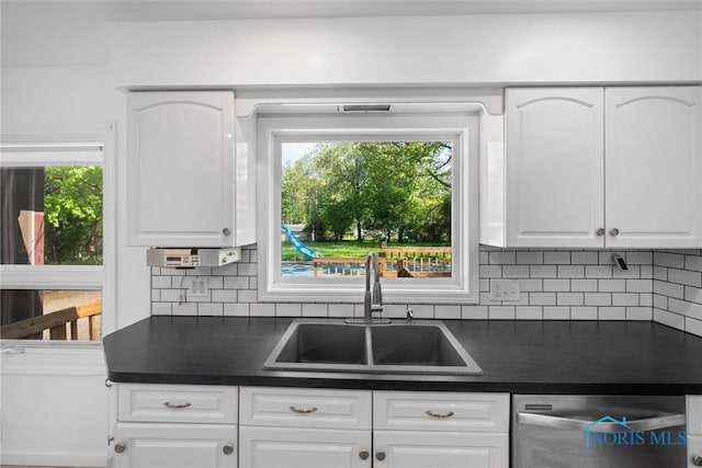 4550 W Sylvania Ave, Toledo, OH 43623 - kitchen with dishwasher, dark countertops, a sink, white cabinets, and decorative backsplash