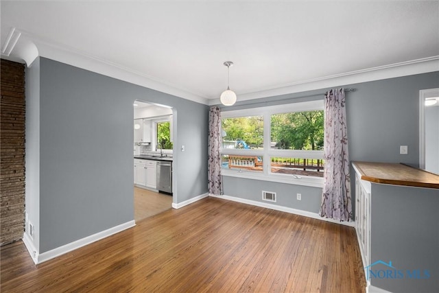 4550 W Sylvania Ave, Toledo, OH 43623 - unfurnished dining area featuring a sink, hardwood / wood-style floors, baseboards, ornamental molding, and arched walkways