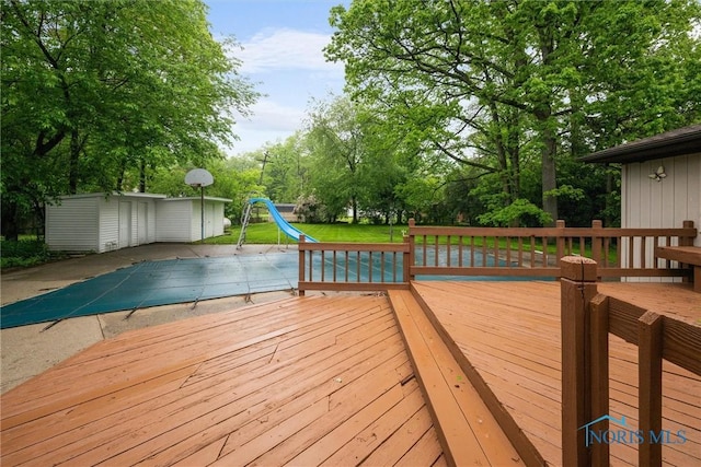 4550 W Sylvania Ave, Toledo, OH 43623 - wooden deck featuring a covered pool, a yard, an outdoor structure, and view of wooded area