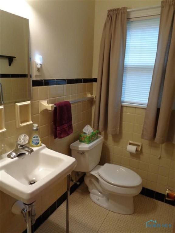 934 E 4th St, Ottawa, OH 45875 - bathroom featuring tile walls, toilet, a sink, and a wainscoted wall