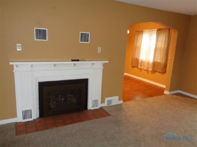 934 E 4th St, Ottawa, OH 45875 - detailed view of carpet flooring, baseboards, a fireplace with flush hearth, and arched walkways