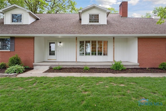 21265 State Route 2, Archbold, OH 43502 - view of front of home featuring a porch, a chimney, a front yard, brick siding, and a shingled roof