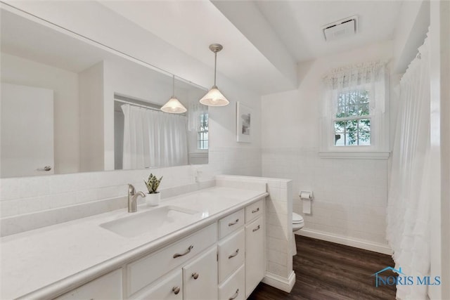 21265 State Route 2, Archbold, OH 43502 - bathroom with healthy amount of natural light, toilet, vanity, wood finished floors, and tile walls