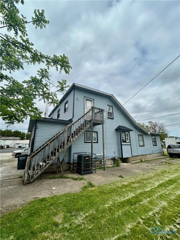 4927 N Summit St, Toledo, OH 43611 - back of house featuring stairway, central air condition unit, and a yard