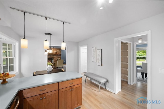 1956 Thornapple Dr, Toledo, OH 43614 - kitchen with a brick fireplace, light wood-style flooring, baseboards, a peninsula, and pendant lighting