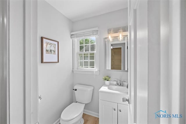 1956 Thornapple Dr, Toledo, OH 43614 - half bathroom with toilet, vanity, baseboards, and wood finished floors
