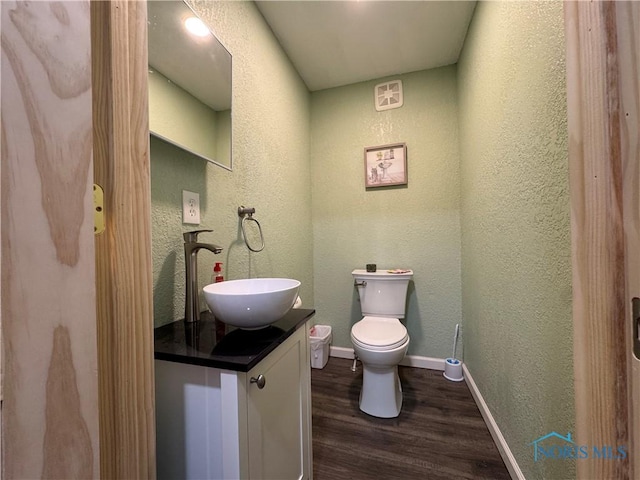 1226 Champe Rd, Toledo, OH 43615 - half bath with a textured wall, vanity, wood finished floors, toilet, and baseboards