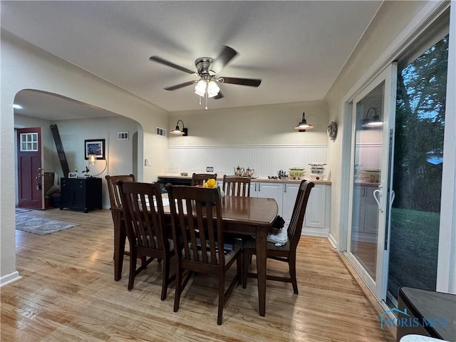 1226 Champe Rd, Toledo, OH 43615 - dining space with arched walkways, a ceiling fan, light wood finished floors, and a wainscoted wall