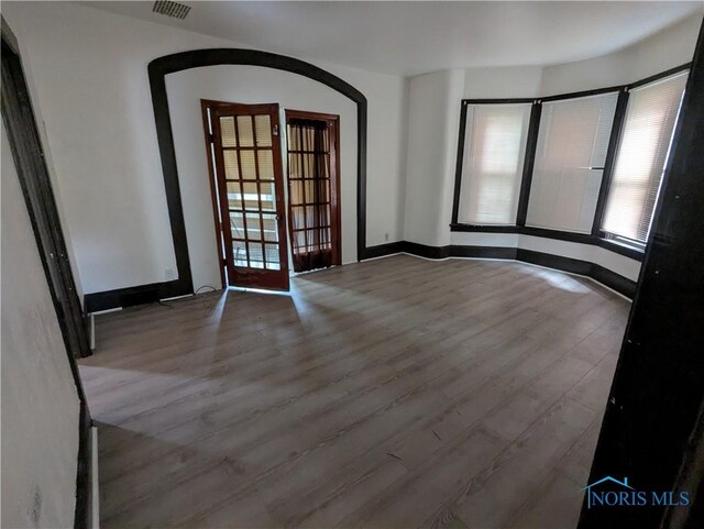 721 N Detroit Ave, Toledo, OH 43607 - empty room with arched walkways, french doors, wood finished floors, and baseboards