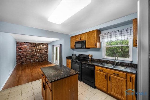 119 Mallard Rd, Perrysburg, OH 43551 - kitchen featuring brick wall, black appliances, a sink, brown cabinets, and a center island