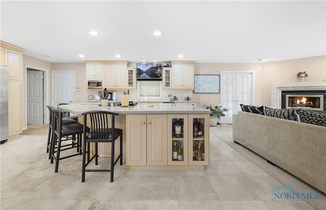 8801 W Bancroft St, Toledo, OH 43617 - kitchen featuring cream cabinets, appliances with stainless steel finishes, a spacious island, a kitchen breakfast bar, and glass insert cabinets
