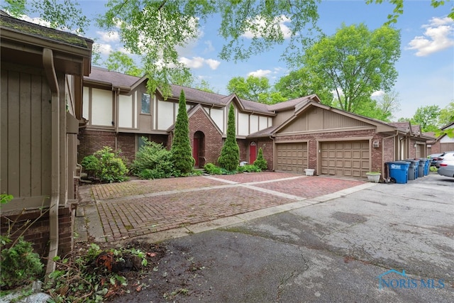 1250 Hidden Ridge Rd, Toledo, OH 43615 - tudor house featuring an attached garage, brick siding, and asphalt driveway