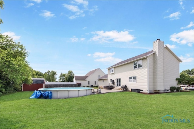 640 Hemlock St, Wauseon, OH 43567 - rear view of property with a chimney, a patio, a yard, an outdoor pool, and a storage shed