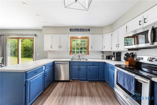 640 Hemlock St, Wauseon, OH 43567 - kitchen with stainless steel appliances, blue cabinetry, a peninsula, plenty of natural light, and recessed lighting
