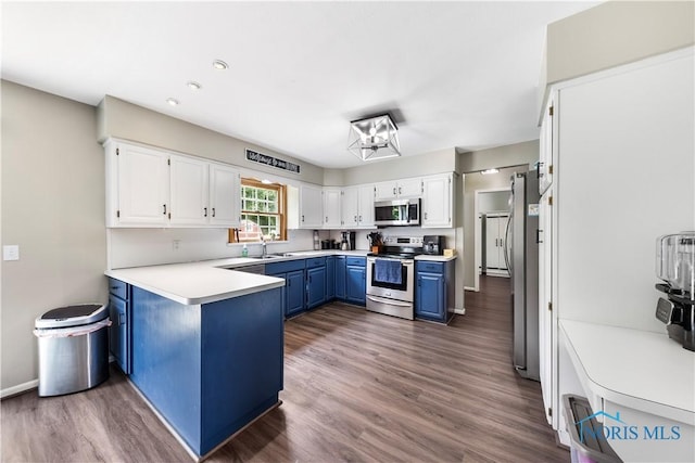 640 Hemlock St, Wauseon, OH 43567 - kitchen with stainless steel appliances, blue cabinetry, white cabinetry, a peninsula, and dark wood-style floors