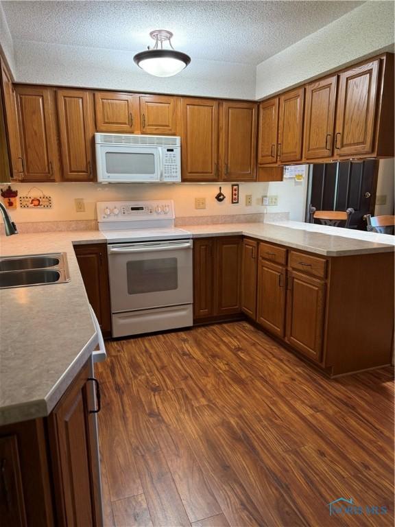 20642 Buckskin Rd, Defiance, OH 43512 - kitchen with white appliances, a sink, dark wood-style flooring, a peninsula, and brown cabinetry