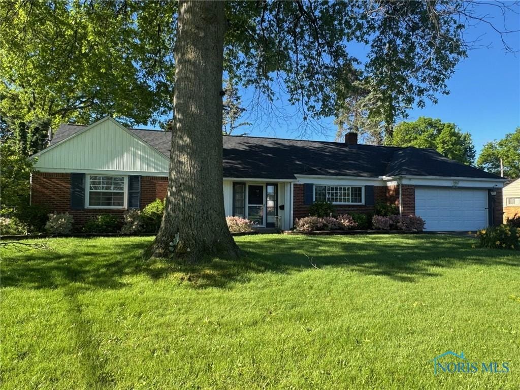3419 Christie Blvd, Toledo, OH 43606 - ranch-style home with brick siding, a garage, and a front yard