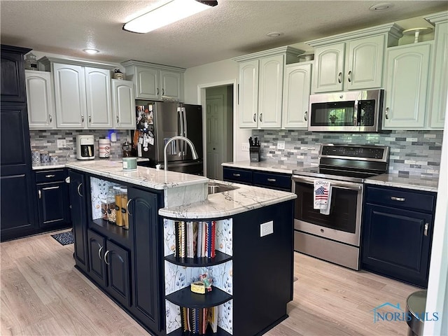 20515 Lockwood Rd, Defiance, OH 43512 - kitchen with appliances with stainless steel finishes, a center island with sink, light wood finished floors, a sink, and tasteful backsplash