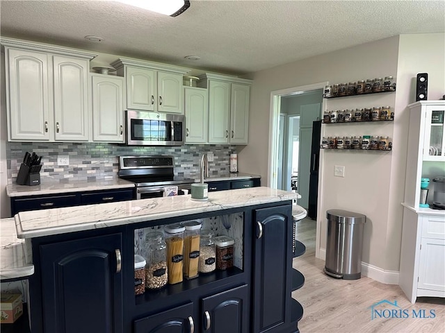 20515 Lockwood Rd, Defiance, OH 43512 - kitchen featuring appliances with stainless steel finishes, light wood-style flooring, tasteful backsplash, a textured ceiling, and light stone counters