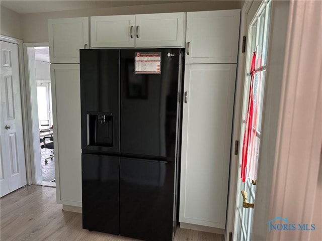 20515 Lockwood Rd, Defiance, OH 43512 - kitchen featuring black fridge, light wood finished floors, and white cabinetry