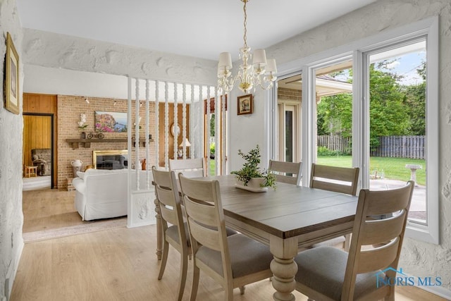 4123 Shamley Green Dr, Toledo, OH 43623 - dining space with light wood-style floors, a chandelier, and a brick fireplace