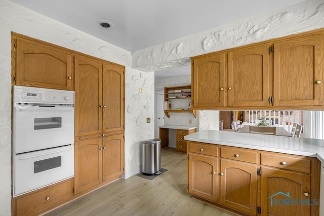 4123 Shamley Green Dr, Toledo, OH 43623 - kitchen with double oven, light wood-style flooring, open shelves, and brown cabinetry