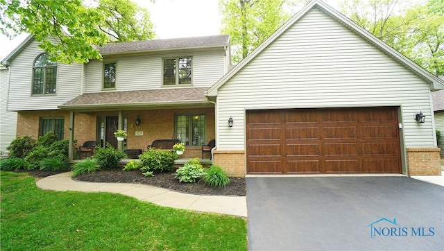 8225 Hidden Forest Dr, Holland, OH 43528 - view of front facade featuring covered porch, driveway, brick siding, a garage, and a front yard