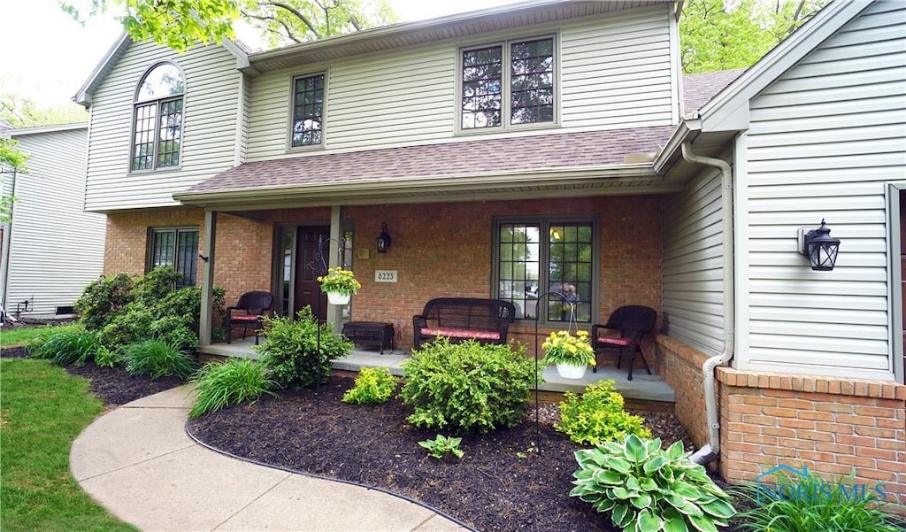 8225 Hidden Forest Dr, Holland, OH 43528 - view of front of house with covered porch, brick siding, and a shingled roof
