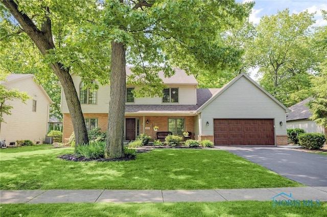 8225 Hidden Forest Dr, Holland, OH 43528 - view of front of home with an attached garage, brick siding, a front lawn, asphalt driveway, and a shingled roof