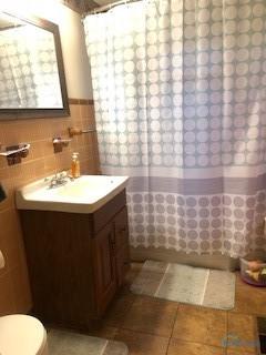 129 Central Ave, North Baltimore, OH 45872 - full bath with vanity, toilet, tile patterned floors, and tile walls