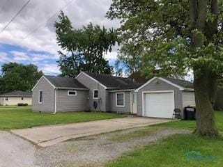 129 Central Ave, North Baltimore, OH 45872 - single story home with concrete driveway, a garage, and a front yard