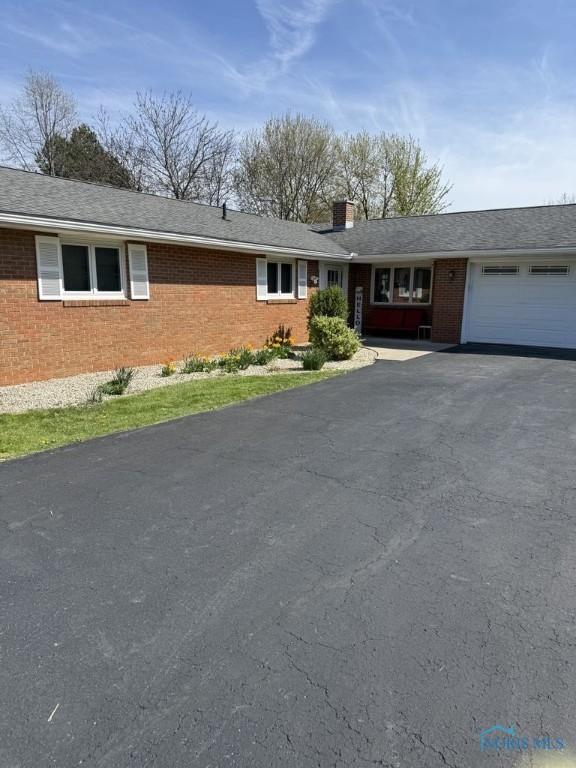 1133 Inverness Dr, Findlay, OH 45840 - ranch-style home featuring a garage, asphalt driveway, brick siding, and a chimney