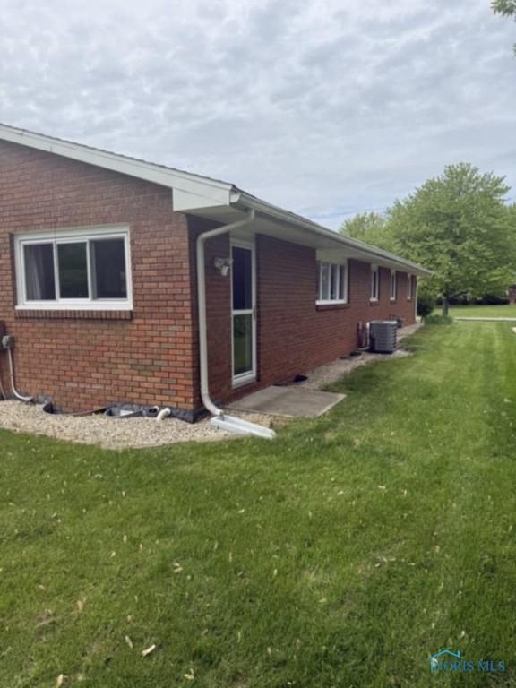 1133 Inverness Dr, Findlay, OH 45840 - view of side of home featuring brick siding, a yard, and central AC
