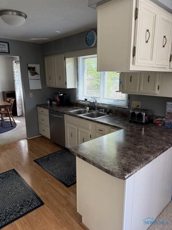 1133 Inverness Dr, Findlay, OH 45840 - kitchen featuring stainless steel dishwasher, dark countertops, a sink, light wood-style flooring, and white cabinetry