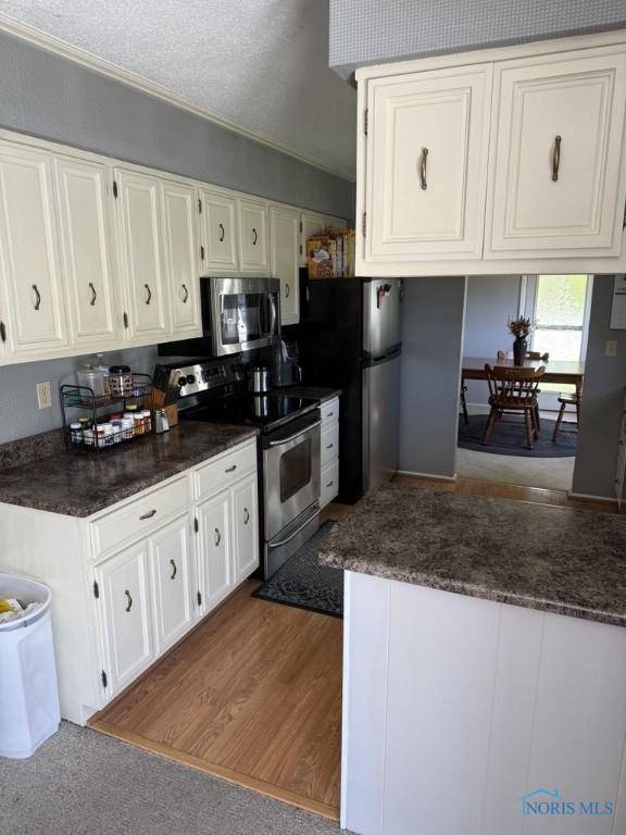 1133 Inverness Dr, Findlay, OH 45840 - kitchen featuring stainless steel appliances, white cabinetry, dark countertops, and a textured ceiling